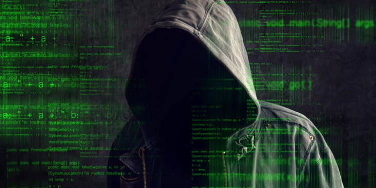 Faceless hooded anonymous computer hacker with programming code from monitor, dark web concept