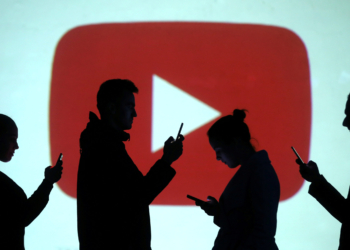 Silhouettes of mobile users are seen next to a screen projection of Youtube logo in this picture illustration taken March 28, 2018.  REUTERS/Dado Ruvic/Illustration - RC1D24345500