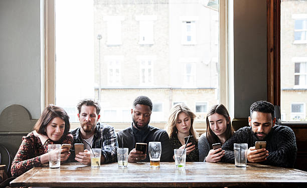 6 friends at a pub with phones, all online, concentrated, having a good time,
